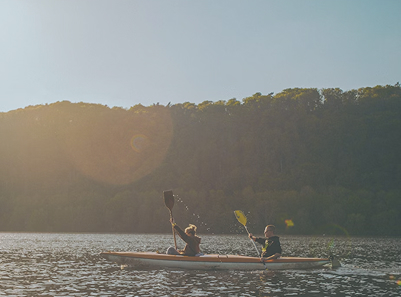 two people kayaking into the sunset